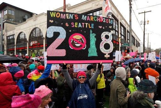 A woman holds as sign as she takes part in a Women's March in Seattle, Saturday, Jan. 20, 2018. The march was one of dozens planned across the U.S. over the weekend. (AP Photo/Ted S. Warren)