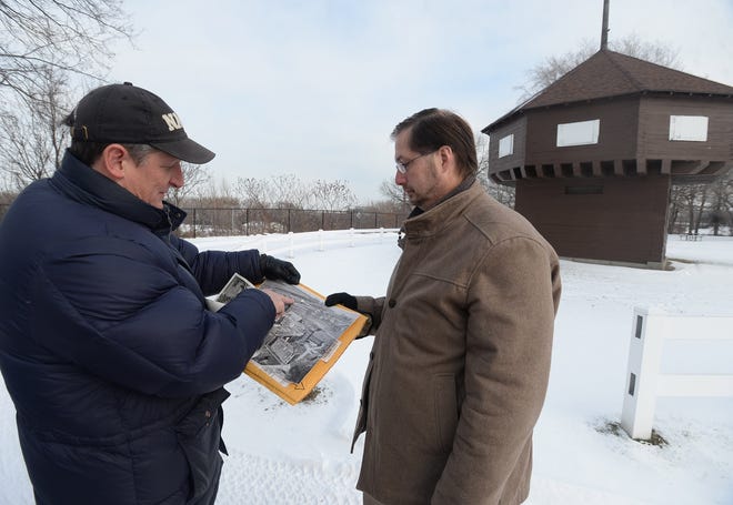 Michael Fuhrman, left, of Erie, and Erie County Councilman Carl Anderson, look at historical photos of the Wayne Blockhouse behind the Pennsylvania Soldiers' and Sailors' Home. The men are involved in an effort to get Fort Presque Isle rebuilt at the site. [JACK HANRAHAN/ERIE TIMES-NEWS]