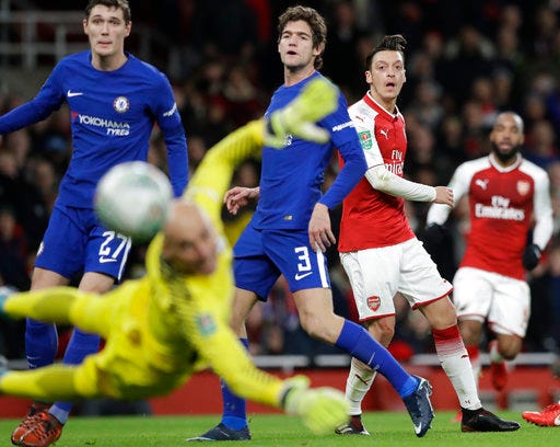 Arsenal's Mesut Ozil, right, shoots during the English League Cup semifinal second leg soccer match between Chelsea and Arsenal at the Emirates stadium in London, Wednesday, Jan.24, 2018. (AP Photo/Matt Dunham)