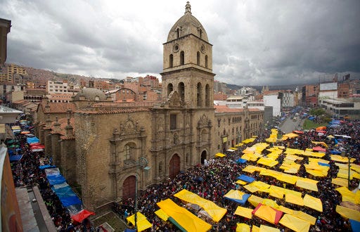 Vendors of miniature items fill the street outside San Francisco Basilica on the first day of the annual Alasita fair in downtown La Paz, Bolivia, Wednesday, Jan. 24, 2018. Thousands people attended the opening day of the fair to buy tiny replicas of things they aspire to acquire during the year, like homes, cars, wealth and love. (AP Photo/Juan Karita)