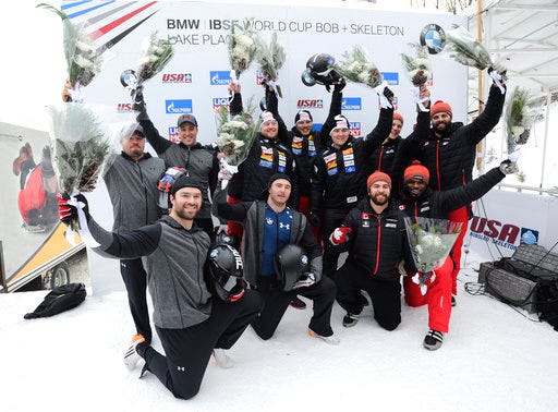 FILE - In this Dec. 17, 2016, file photo, the Swiss team of Rico Peter, Janne Bror van der Zijde, Simon Friedli and Thomas Andrianov, center rear, celebrates its win in the four-man bobsled World Cup race in Lake Placid, N.Y. The U.S. team of Steven Holcomb, rear left, Carlo Valdes, James Reed and Sam McGuffie, front left, took second place. Canada's Chris Spring, Cameron Stones, Lascelles Brown and Samuel Giguere took third place. McGuffie has scored at Notre Dame Stadium. Little did he know he was on a path to the Olympics. McGuffie was a running back at Michigan and Rice, bounced around some NFL and CFL clubs, then got told about bobsledding. Not long afterward, he met Steven Holcomb _ and this season, McGuffie's first Olympic season, has been a tribute to his late friend.(AP Photo/Hans Pennink, File)