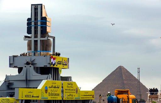 A drone hovers as a statue of Egyptian Pharaoh Ramses II is relocated at the Grand Egyptian Museum near the great Pyramids, in Cairo, Egypt, Thursday, Jan. 25, 2018. The museum is scheduled to open later this year. Arabic at top reads, "long live Egypt." (AP Photo/Amr Nabil)