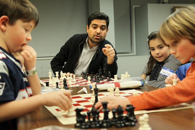 Instructor Farzad Abdi gives advice as Henry Smith, 7, Jaelyn Gacicia, 7 and Charlie Melia, 8, make their moves. The Hingham Chess Club attracts many youths to the Hingham Library, Thursday, Jan. 25, 2018. 

Gary Higgins/The Patriot Ledger