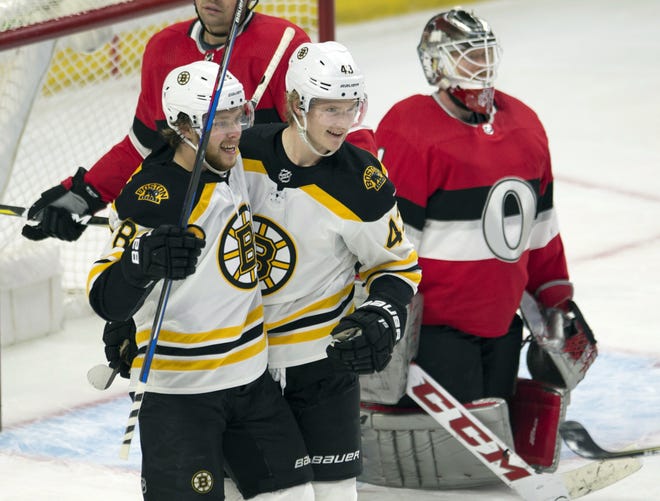 Bruins right wing David Pastrnak (88) congratulates center Danton Heinen on his goal as Senators goalie Mike Condon looks on during the second period on Thursday night. [Adrian Wyld/The Canadian Press via AP]