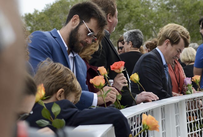 Tal Ramon, son of space shuttle Columbia astronaut Ilan Ramon, and other friends and family of fallen astronauts place flowers in the fence at the Space Mirror Memorial at Kennedy Space Center Visitor Complex on Thursday during Kennedy Space Center's annual day of remembrance. The annual event honors those who perished in the space program. [Craig Bailey/Florida Today]