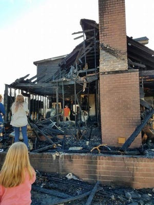 The Sharpe family stands by their home of three years after it went up in flames Wednesday. [Special to The Star]