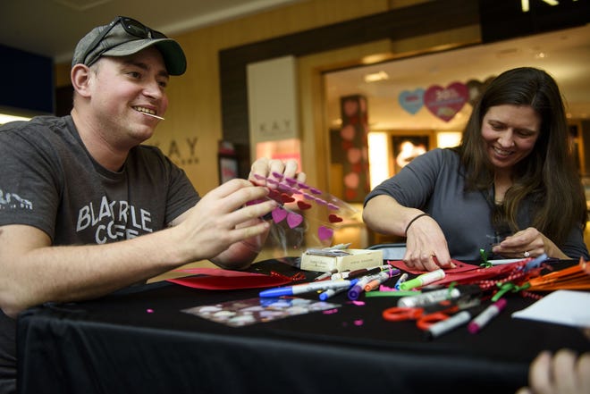 Capt. Greg O'Morrissey, left, from Fort Lee, Virginina, and Clarissa Gosclej make Valentine's Day cards for veterans at Cross Creek Mall on Saturday. [Melissa Sue Gerrits/The Fayetteville Observer]