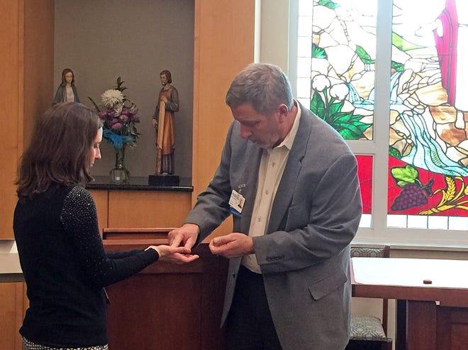 Hospital staff Christy Rizza receives anointing from Chaplain Jeff Carlton during the recommitment ceremony. The anointing of the hands with oil is especially meaningful to physicians, nurses and other hospital staff. [SPECIAL TO THE LOG]