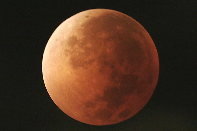 In this Aug. 28, 2007, file photo, the moon takes on different orange tones during a lunar eclipse seen from Mexico City. During a lunar eclipse, the moon's disk can take on a colorful appearance from bright orange to blood red to dark brown and, rarely, very dark gray. On Wednesday, Jan. 31, 2018, a super moon, blue moon and a lunar eclipse will coincide for first time since 1982 and will not occur again until 2037. (AP Photo/Marco Ugarte, File)