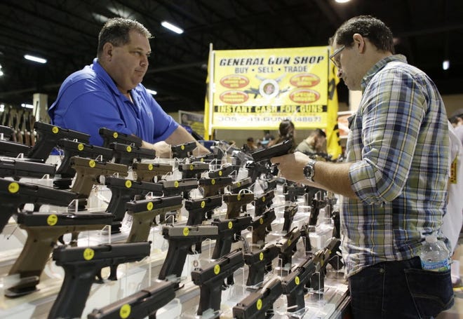 A customer looks at handguns at a gun show in Miami. [AP Photo/Lynne Sladky, File]