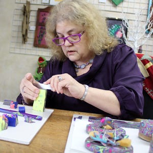 Rhonda Foster demonstrates how she cuts a thin layer of clay to cover a trinket box. [NANCY HASTINGS PHOTO]