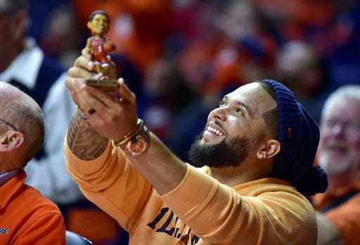 Former Illinois player Deron Williams holds up a bobblehead of himself Tuesday during a timeout in the game between Illinois and Rutgers at State Farm Center. [Stephen Haas/The Associated Press]