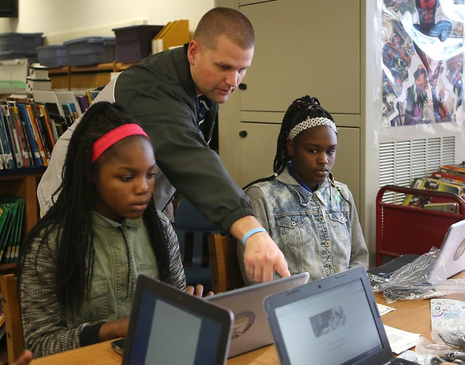 Ryan Anderson helps Leiona Boles and Cherish Walker set up their new Chromebooks on Thursday at Everitt Middle School. [PATTI BLAKE/THE NEWS HERALD]