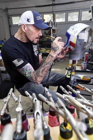 Jason Livery works on one of two hockey masks that will be used by the U.S. hockey team in the 2018 Winter Olympics. Livery, owner of HeadStrongGrafx in Niceville, has painted custom hockey masks for a wide variety of professional and collegiate goaltenders. [DEVON RAVINE/DAILY NEWS]