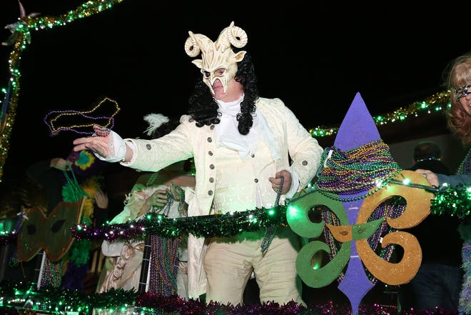 A man on a float throws beads to the crowd at the Leesburg Mardi Gras parade Saturday in downtown Leesburg. [BOB SNOW / CORRESPONDENT]