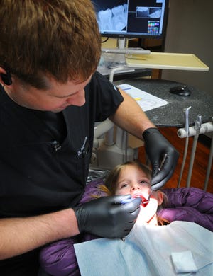 Dr. Jason Barth examines Ava Hedstrom, 6, Friday morning during Give Kids A Smile, a free dental clinic at Salina Dental Arts. [TOM DORSEY / SALINA JOURNAL]