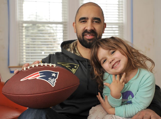 Rafael Hernandez with his daughter, Valerie, 3, and his lucky Patriots Super Bowl football, which he keeps with him for good luck when watching the game. [Steve Heaslip/Cape Cod Times]
