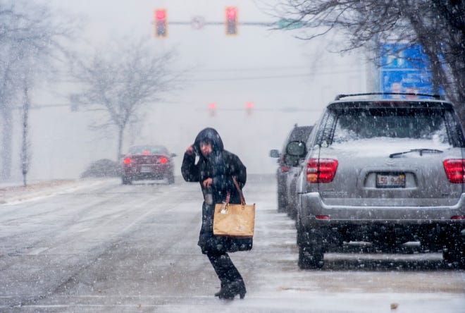 DAVID ZALAZNIK/JOURNAL STAR A woman battles gusts of wind while crossing Hamilton Boulevard Sunday in a snow squall that hit Peoria.