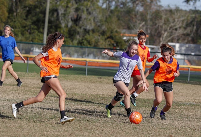 Mount Dora varsity girls soccer player Olivia Novotny splits defenders during practice, Monday in Mount Dora. [BOB SNOW / CORRESPONDENT]