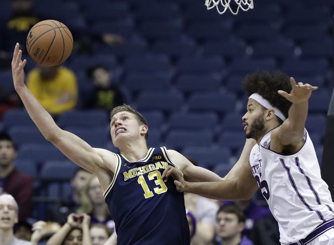 Michigan forward Moritz Wagner, left, reaches for a rebound next to Northwestern center Barret Benson during the first half Tuesday, Feb. 6, 2018, in Rosemont. [NAM Y. HUH/THE ASSOCIATED PRESS]