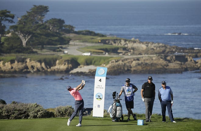 Rory McIlroy hits from the fourth tee of the Spyglass Hill Golf Course during the first round of the AT&T Pebble Beach National Pro-Am golf tournament Thursday, Feb. 8, 2018, in Pebble Beach, Calif. Looking on, second from right, is Phil Mickelson and at right is Jimmy Dunne III. [Eric Risberg/The Associated Press]