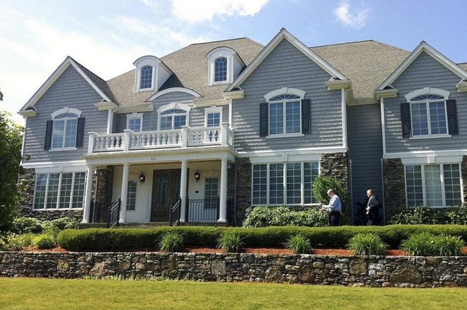 FILE - In this June 19, 2013 file photo, two members of the Massachusetts State Police walk toward the front door of the home of New England Patriot's NFL football player Aaron Hernandez in North Attleborough, Mass. The home was sold in November 2017 to 23-year-old real estate investor Arif Khan for $1 million, about $300,000 lower than the asking price. [AP Photo/ Erika Niedowski, File]