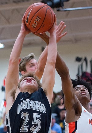 Ledford's Walker Lackey muscles down a rebound against North Davidson's Themus Fulks (right) and Satchel Hester on Friday night. [Donnie Roberts/The Dispatch]