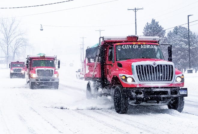 A trio of city of Adrian trucks begin plowing streets on Friday.
