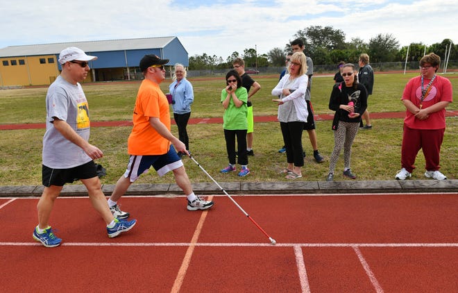 Special Olympics athlete Jonathan Chace, in orange shirt, walks on the track during a practice session for athletes on Saturday, Feb. 3, 2018, at the Gene Whipp Sports Center in Venice. Chace, who is blind, plans to compete in the 400-meter walk and the shot put at the Sarasota County Games, to be held Saturday, Feb. 17, 2018, at Pine View School in Osprey. Chace is guided by fellow athlete and friend, Doug Johnson, far left, who is also blind. The men joke that it's "the blind leading the blind" when they walk the track together. [Herald-Tribune staff photo / Mike Lang]