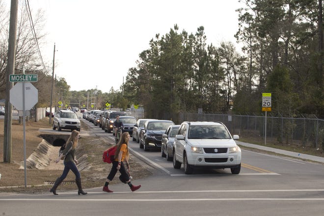 Students walk through a four-way stop outside Mosley High School on Thursday. A roundabout is planned for the intersection, where traffic frequently is backed up all the way from State 77 during peak school traffic hours. [JOSHUA BOUCHER/THE NEWS HERALD]
