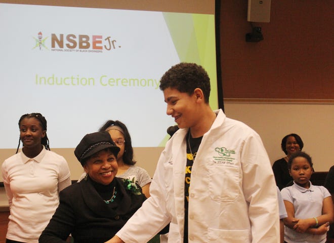 President of the Petersburg Links Incorporated Rose Bland Muse gives a special white lab coat to Petersburg student Eric Dabney on Feb. 13, 2018. Dabney was one of 38 Petersburg students being inducted into the newly created Petersburg chapter of the National Society of Black Engineers Jr. [John Adam/progress-index.com]