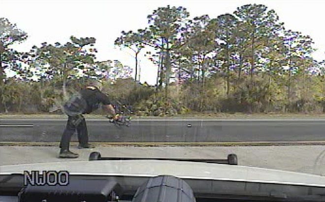 A Fellsmere Police Department officer throws stop sticks out onto the northbound lanes of Interstate 95 in an effort to halt a runaway BMW SUV on Monday, Feb. 12, 2018. The driver, Joseph Cooper of Palm Coast, called 9-1-1 to report he could not slow down. [Fellsmere Police Department]