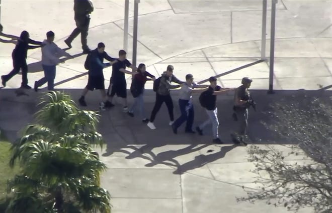 In this frame grab from video provided by WPLG-TV, students from the Marjory Stoneman Douglas High School in Parkland, Fla., evacuate the school following a shooting, Wednesday, Feb. 14, 2018. (WPLG-TV via AP)