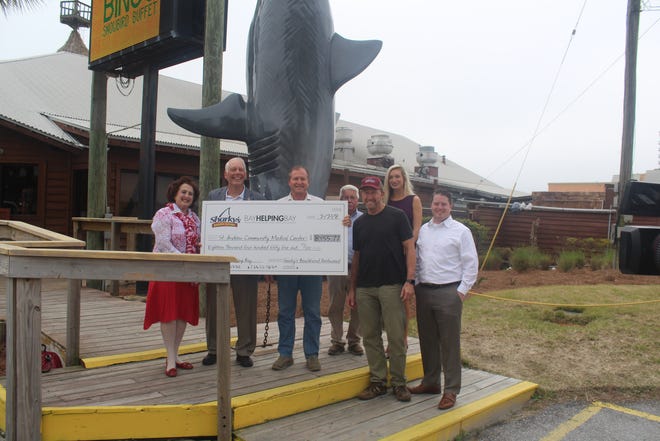 Representatives of Sharky’s Beachfront Restaurant present an $18,477 check to representatives of St. Andrews Community Medical Center. The money was raised through January’s Bay Helping Bay event at Sharky’s. From left are Carole and Delbert Summey with the clinic; Derrick Bennett, Sharky’s co-owner; Rick Hulse; Neel Bennett, Sharky’s co-owner; Kami Viers and Grant B. Wittstruck. [MICHAEL McCABE/THE NEWS HERALD]