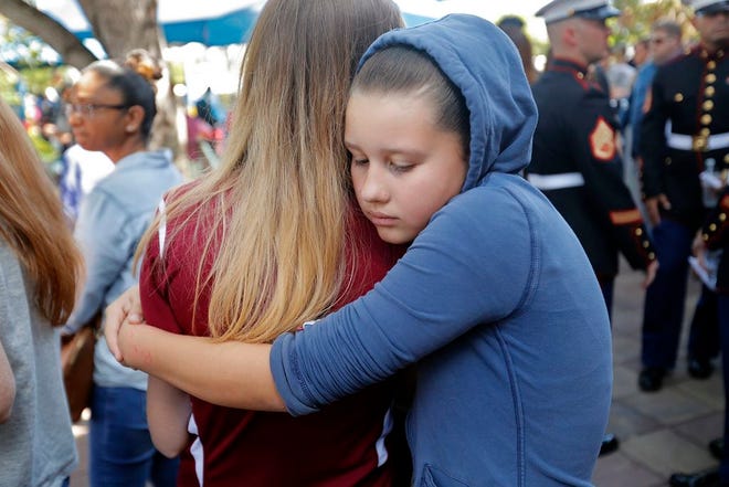 Kaitlynn Cooper, 12, facing, hugs her friend Allison Shonk, 18, a student at Marjory Stoneman Douglas High School, during a vigil at the Parkland Baptist Church, in Parkland, Fla., Thursday, Feb. 15, 2018. Nikolas Cruz, a former student, was charged with 17 counts of premeditated murder Thursday morning.