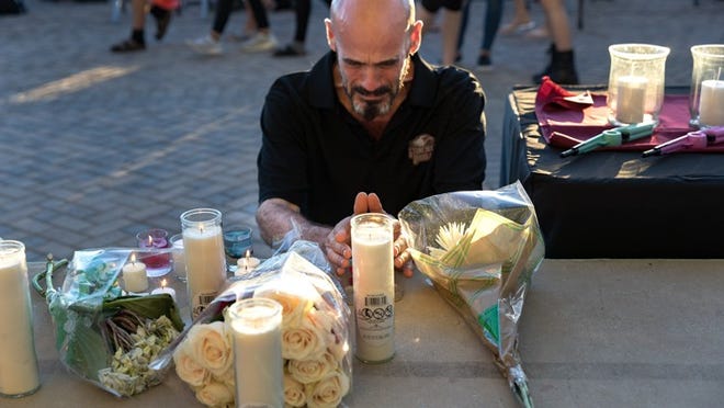 Kevin Siegelbaum, who has taught special education at Marjory Stoneman Douglas High School for 2 1/2 years, prays in front of flowers, candles and tributes on the stage at Pine Trails Park for the victims of the mass shooting at Marjory Stoneman Douglas High School, in Parkland, Thursday. (Greg Lovett / The Palm Beach Post)