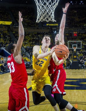 Michigan guard Duncan Robinson (22) attempts to make a basket, defended by Ohio State forward Keita Bates-Diop (33) and forward Kyle Young, right, in the first half of an NCAA college basketball game at Crisler Center in Ann Arbor, Mich., Sunday, Feb. 18, 2018. (AP Photo/Tony Ding)