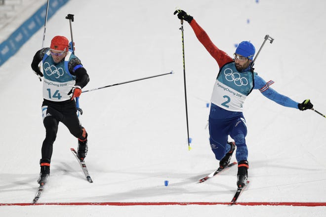Simon Schempp, of Germany, left, and Martin Fourcade, of France, right, race across the finish line during the men's 15-kilometer mass start biathlon at the 2018 Winter Olympics in Pyeongchang, South Korea, on Sunday. Fourcade won. [Andrew Medichini/The Associated Press]