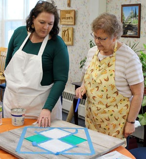 Instructor Carol Briner offers color suggestions for Betsy Brooks during a barn quilt class at GIG. [NANCY HASTINGS PHOTO]
