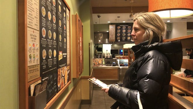 Bethany Doerfler, a registered dietitian at the Digestive Health Center at Northwestern Medicine, looks at a fast food menu. [GRACE WONG/CHICAGO TRIBUNE]