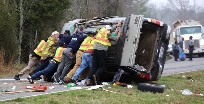 Emergency responders push to flip an overturned vehicle back on its wheels on East Zion Church Road on Monday. A child was sent to a Charlotte hospital as a result of the wreck. [Brittany Randolph/The Star]