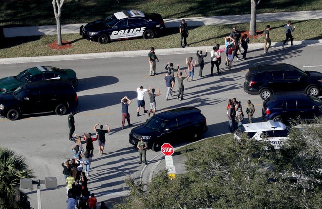 Students hold their hands up as they are evacuated by police from Marjory Stoneman Douglas High School in Parkland on Feb. 14 after the shooter opened fire on campus. [Mike Stocker/South Florida Sun-Sentinel via AP, File]