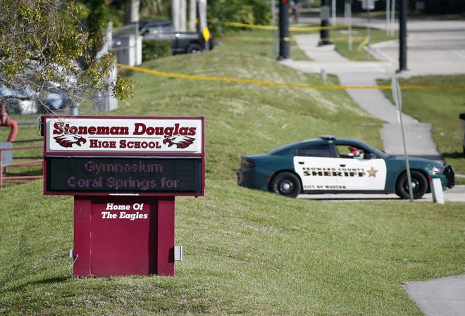 FILE- In this Feb. 15, 2018, file photo, Law enforcement officers block off the entrance to Marjory Stoneman Douglas High School, in Parkland, Fla., a deadly shooting at the school. A large Wall Street money manager wants to engage with major weapons manufacturers about their response to the school massacre in Parkland. (AP Photo/Wilfredo Lee, File)