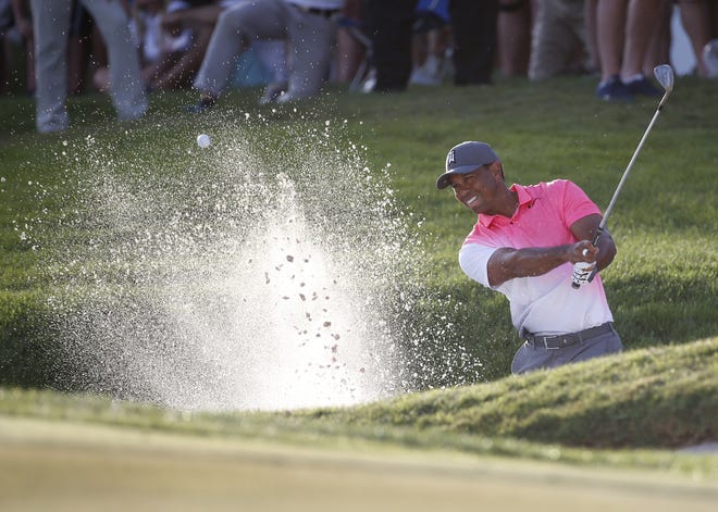 Tiger Woods hits out of a bunker on the 18th hole during the second round of the Honda Classic on Friday in Palm Beach Gardens. [AP Photo / Wilfredo Lee]