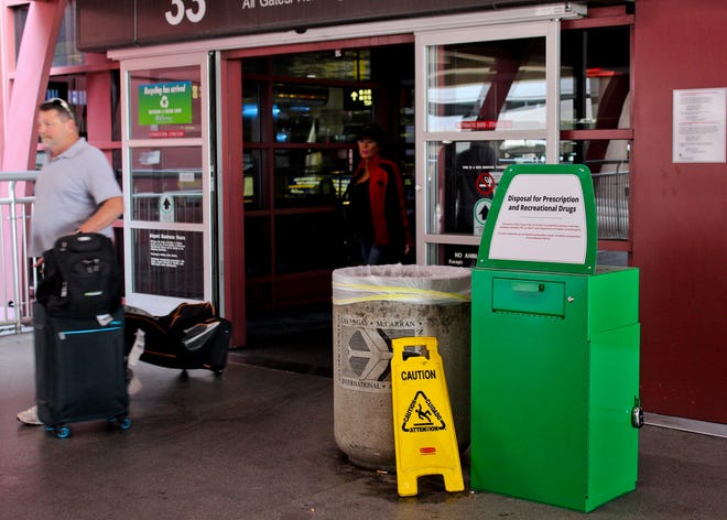 Unidentified travelers exit the airport past a green metal container designed for "Disposal for Prescription and Recreational Drugs," set outside one of the entrances to McCarran International Airport in Las Vegas, Thursday, Feb. 22, 2018. People catching a flight at the airport can now get rid of prescription and recreational drugs, before entering the Clark County-Department of Aviation-owned property, thanks to the receptacles commonly referred to as "amnesty boxes." The first of about 20 green metal containers commonly referred to as amnesty boxes were installed earlier this month in response to county officials banning marijuana possession and advertising at the airport last year. (AP Photo/Regina Garcia Cano)