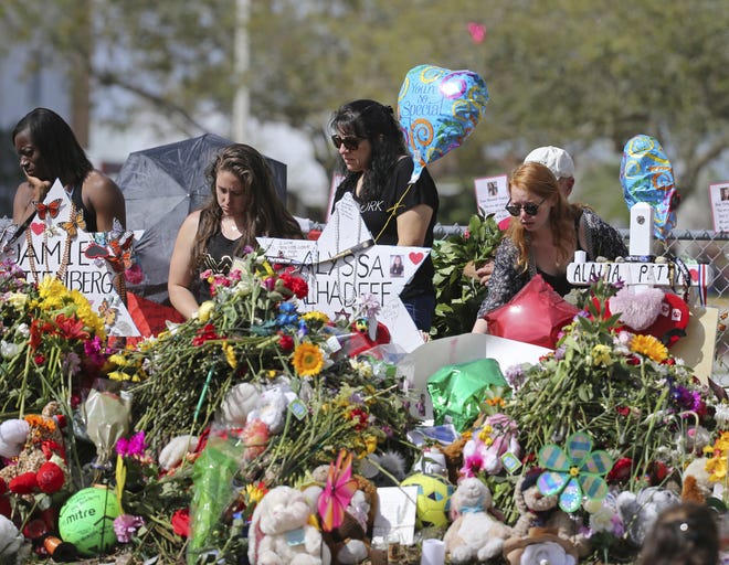 Mourners bring flowers as they pay tribute at a memorial for the victims of the shooting at Marjory Stoneman Douglas High School on Sunday in Parkland. [David Santiago/Miami Herald via AP]