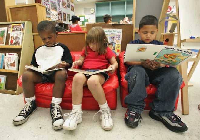 Three children, all age 4, looks though books while attending a pre-kindergarten program. [GateHouse Media, File]