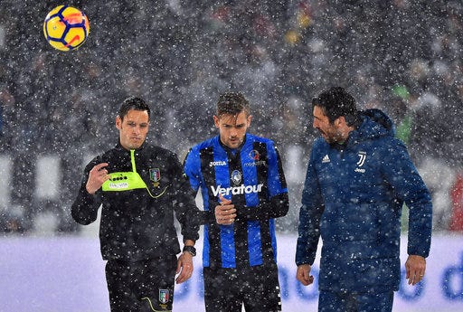 From left, referee Maurizio Mariani, Atalanta's Rafael Toloi and Juventus goalie Gianluigi Buffon walk on the pitch of the Allianz Stadium in Turin, Italy, Sunday, Feb. 25, 2018. Snowfall has prompted the Serie A match between six-time defending champion Juventus and Atalanta to be postponed. Fans filled the Allianz Stadium shortly before the scheduled kickoff Sunday but when the referee could not roll the ball on the snow-covered pitch, the game was quickly called off. (Alessandro Di Marco/ANSA via AP)