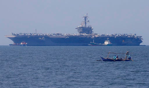 FILE - In this Feb. 17, 2018, file photo, fishermen on board a small boat pass by the USS Carl Vinson aircraft carrier at anchor off Manila, Philippines, for a five-day port call. The USS Carl Vinson will reportedly make a historic visit to Vietnam in March 2018 as part of the Navy’s largest multinational disaster response exercises in the Indo-Pacific region. (AP Photo/Bullit Marquez, File)