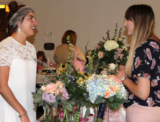 Jackie Raeff talks with Ellie Stewart of Smith's Flowers during the Bridal Expo held Sunday in Jonesville. [NANCY HASTINGS PHOTO]